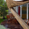 Terrazza con sedie e tavolo in legno, circondata dal verde.
