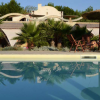 Piscina con lettini e piante verdi intorno.
