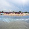 Spiaggia vista dal mare con ombrelloni e torre sullo sfondo.