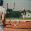 Due persone giocano a tennis su un campo all'aperto.