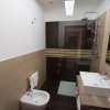 Bagno moderno con doccia in vetro, lavabo e bidet su pavimento scuro.