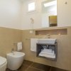 Bagno moderno con lavabo, bidet e wc. Pareti beige e dettagli bianchi.