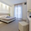 Camera da letto luminosa con letto matrimoniale, comodini e vasi decorativi.