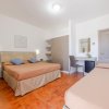 Camera da letto con due letti, uno matrimoniale e uno singolo, su pavimento in piastrelle rosse.