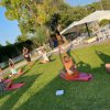 Persone praticano yoga su tappetini rosa all'aperto su un prato.