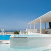 Piscina all'aperto con area relax coperta e vista mare.