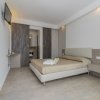 Camera moderna con letto matrimoniale, armadio a muro e pavimento in legno chiaro.