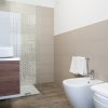 Bagno moderno con doccia, lavabo su mobile in legno, bidet e water con asciugamano bianco.