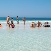 Persone si divertono in mare poco profondo sotto un cielo sereno.
