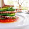 Fette di polpo e zucchine su salsa rossa in un piatto.