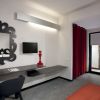 Interno di una camera da letto moderna con scrivania, specchio decorativo e tenda rossa.