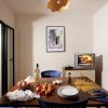 Una cucina con un tavolo apparecchiato con frutta, uova, vino e pasta, e una piccola TV accesa.