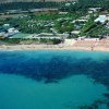 Spiaggia e mare turchese davanti a un villaggio turistico.