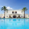 Piscina luminosa davanti a una villa bianca con palme.