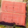 Due campi da tennis in terra rossa, vista dall'alto.