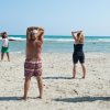 Persone fanno stretching su una spiaggia sabbiosa.