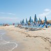 Spiaggia con sdraio e ombrelloni blu.