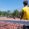 Persone giocano a tennis su un campo all'aperto.