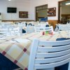 Ristorante con tavoli apparecchiati e sedie bianche.