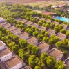 Vista aerea di bungalow tra alberi, piscina sullo sfondo.
