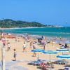 Spiaggia animata con ombrelloni gialli e blu.